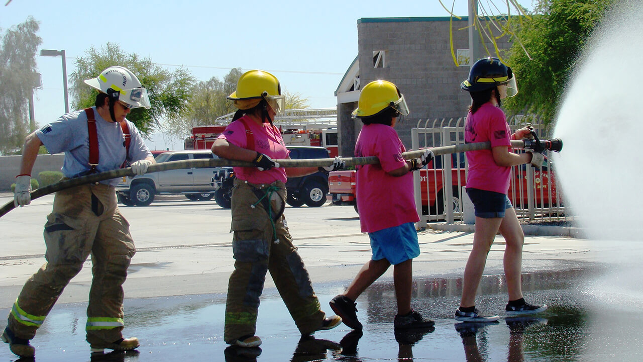 Young girls advancing a hose.